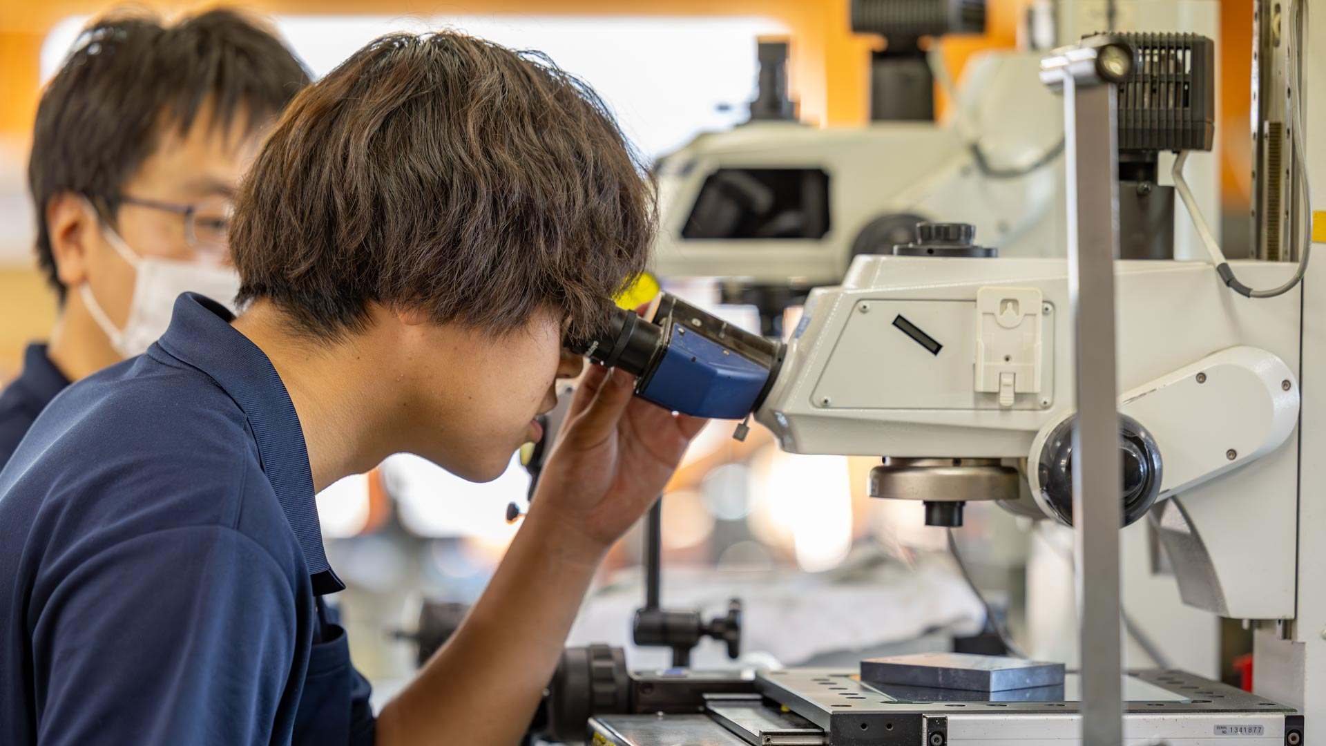 工場内で設計図面を確認しながら作業を行う技術者