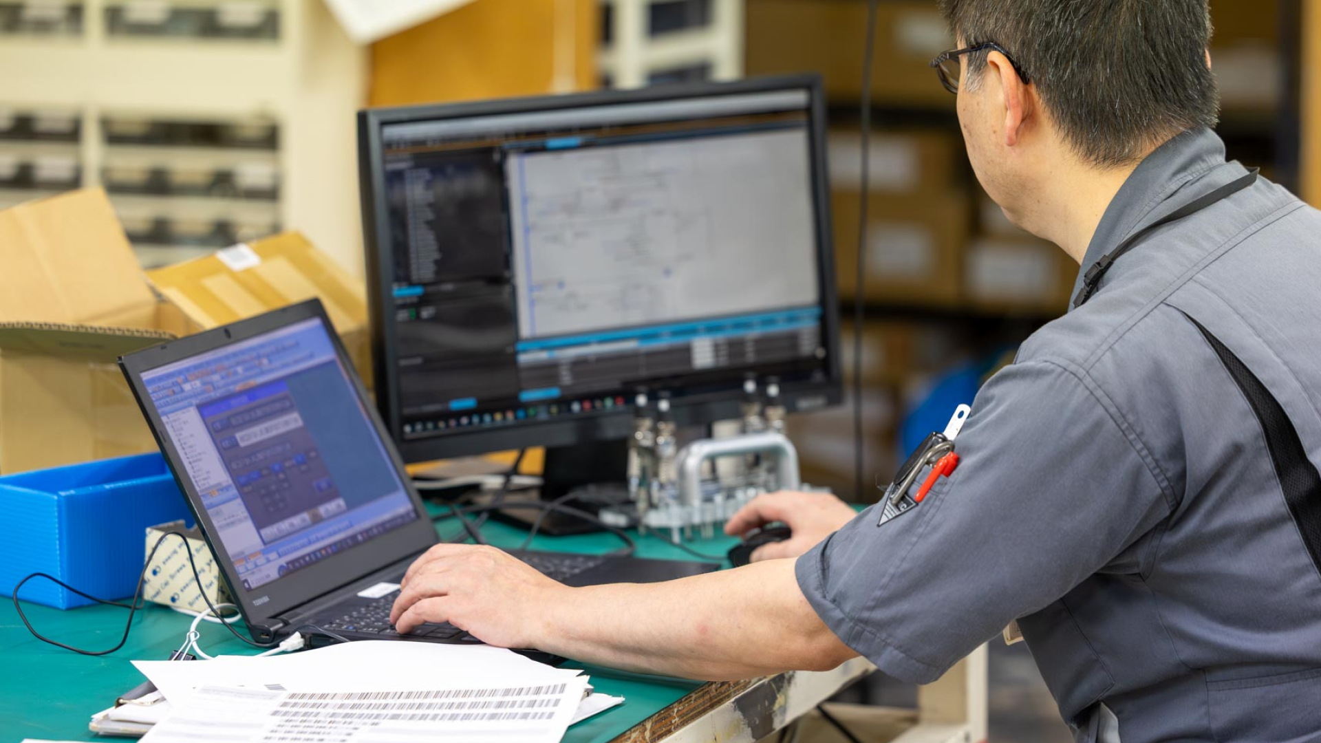 工場内で設計図面を確認しながら作業を行う技術者